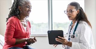 A female doctor shows a female patient information on a tablet